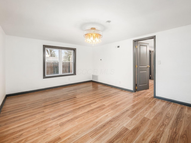 unfurnished room with light hardwood / wood-style flooring and a notable chandelier