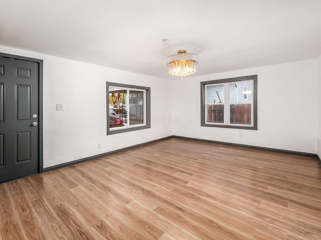 unfurnished room with light hardwood / wood-style floors and an inviting chandelier