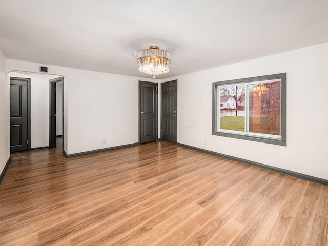 unfurnished room featuring light hardwood / wood-style flooring and a notable chandelier