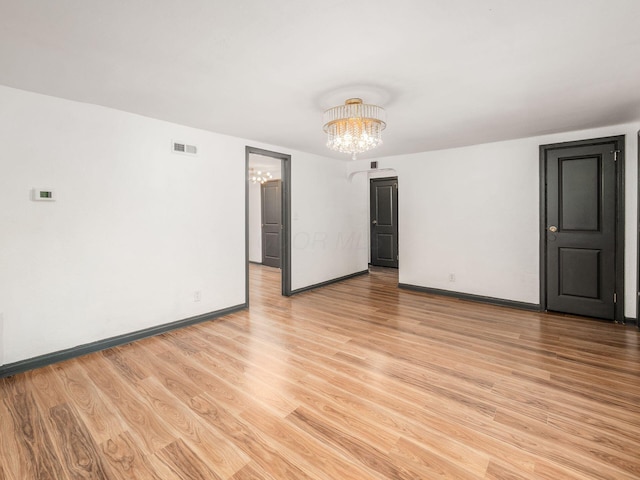 unfurnished room with light hardwood / wood-style floors and a notable chandelier