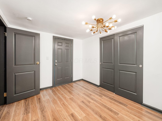 unfurnished bedroom with a closet, a chandelier, and light wood-type flooring