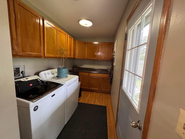 clothes washing area featuring washing machine and dryer, cabinets, a textured ceiling, and light hardwood / wood-style floors