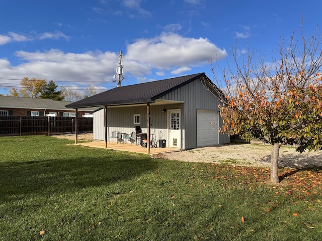 back of house with a lawn, a patio, an outdoor structure, and a garage