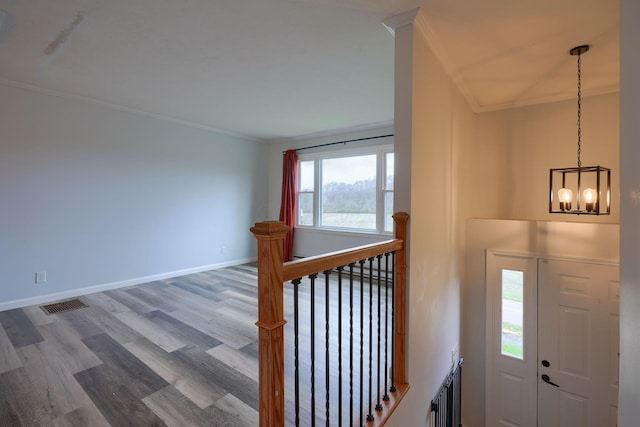 foyer with an inviting chandelier, wood-type flooring, and ornamental molding