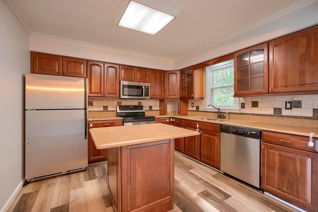 kitchen featuring appliances with stainless steel finishes, crown molding, sink, a center island, and light hardwood / wood-style floors