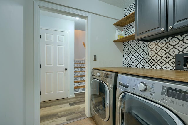 washroom featuring cabinets, washing machine and dryer, and light wood-type flooring