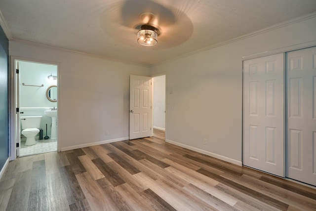 unfurnished bedroom featuring ensuite bathroom, crown molding, ceiling fan, and hardwood / wood-style flooring