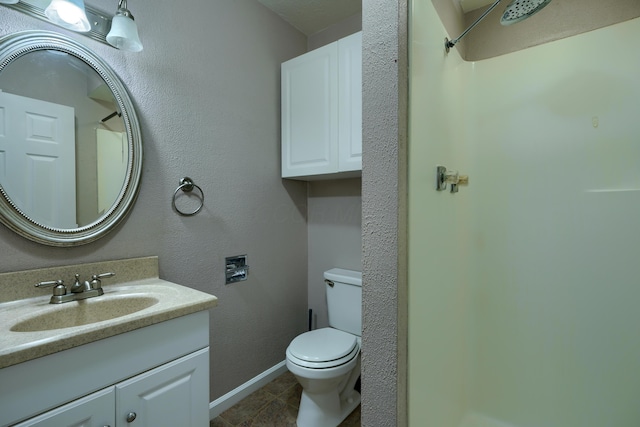 bathroom with tile patterned floors, vanity, toilet, and walk in shower