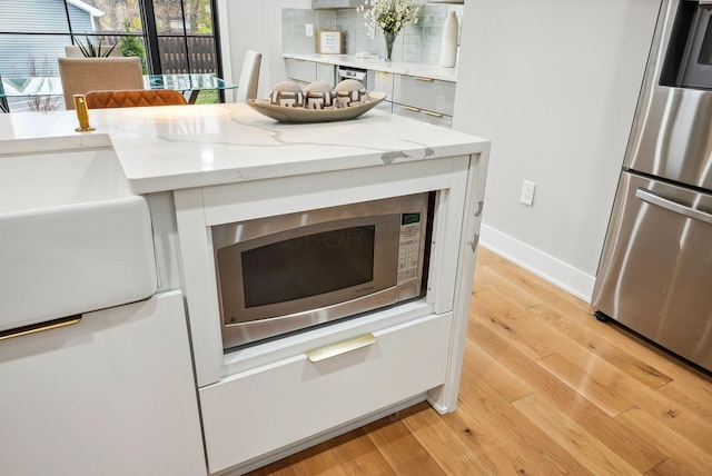 interior details with light stone countertops, light hardwood / wood-style flooring, and stainless steel appliances