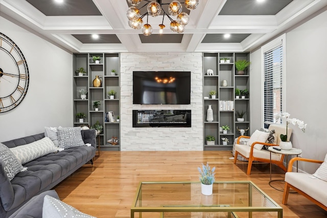 living room with hardwood / wood-style floors, coffered ceiling, a stone fireplace, a notable chandelier, and beam ceiling