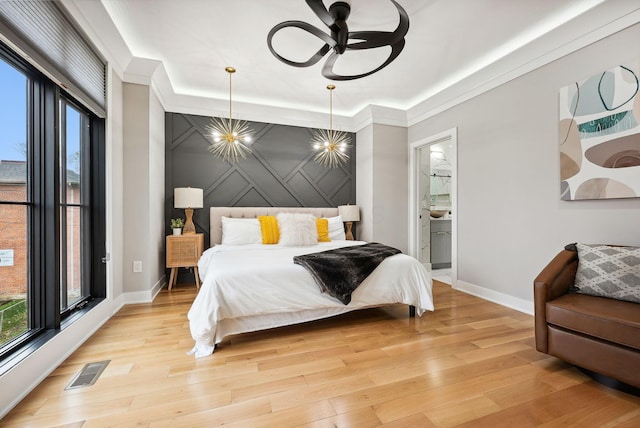 bedroom featuring ensuite bathroom, light wood-type flooring, and crown molding