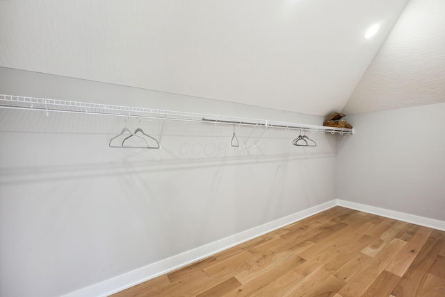 walk in closet with hardwood / wood-style floors and vaulted ceiling