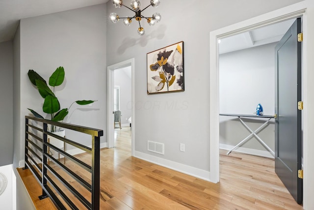 corridor with hardwood / wood-style floors and an inviting chandelier