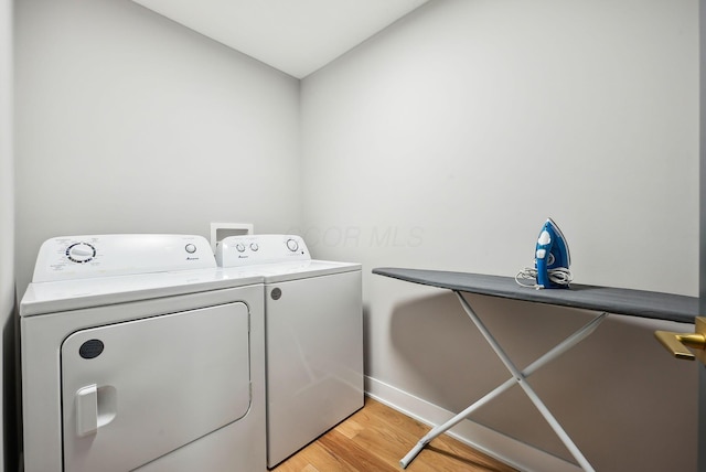 laundry area featuring washer and dryer and light hardwood / wood-style flooring