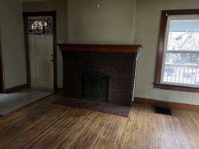 unfurnished living room with hardwood / wood-style floors and a brick fireplace