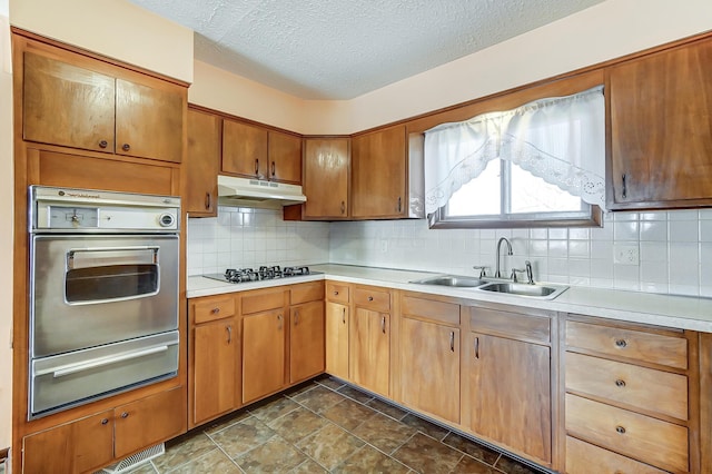 kitchen featuring gas cooktop, tasteful backsplash, stainless steel oven, a textured ceiling, and sink