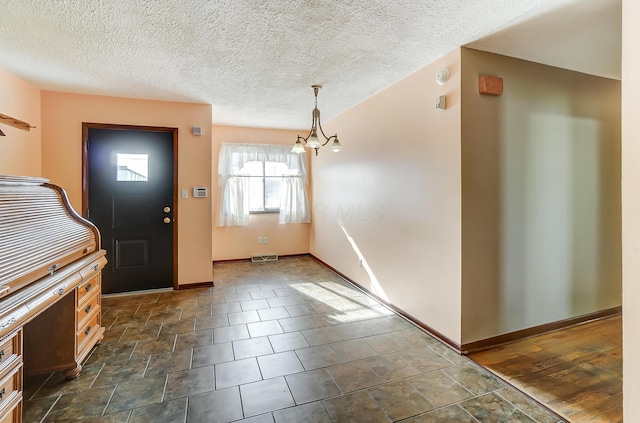 foyer entrance featuring a textured ceiling, dark hardwood / wood-style floors, and a notable chandelier