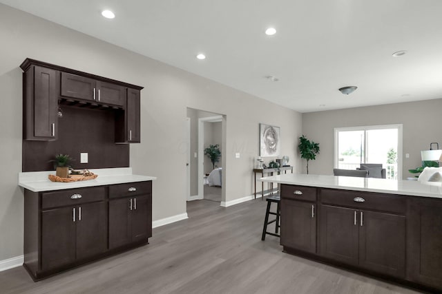 kitchen with dark brown cabinets, light wood-type flooring, and a breakfast bar