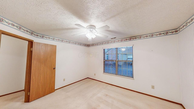 unfurnished room with carpet flooring, ceiling fan, and a textured ceiling