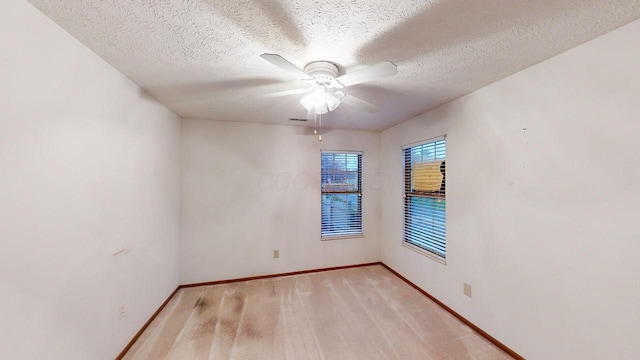 carpeted spare room featuring a textured ceiling and ceiling fan