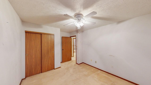 unfurnished bedroom with ceiling fan, light colored carpet, a textured ceiling, and a closet