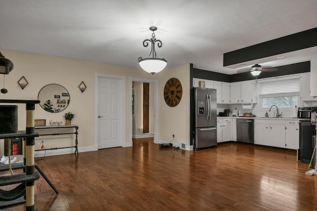 kitchen with pendant lighting, white cabinetry, stainless steel appliances, and dark wood-type flooring