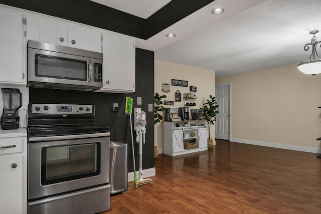 kitchen with dark wood-type flooring, white cabinets, stainless steel appliances, and decorative light fixtures