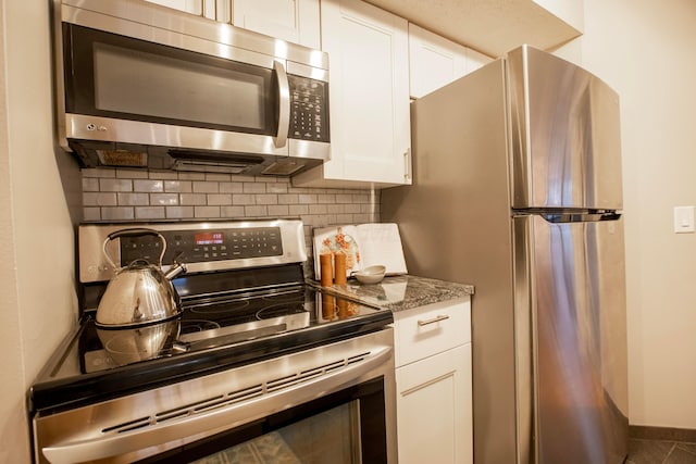 39 Buttles Ave Unit 39, Columbus, OH 43215 - kitchen with appliances with stainless steel finishes, decorative backsplash, white cabinets, and light stone counters