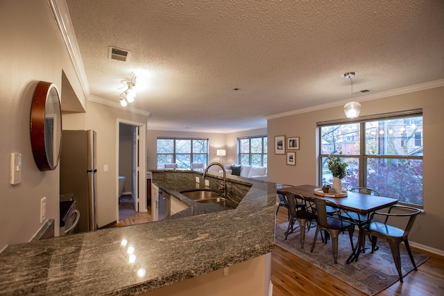 39 Buttles Ave Unit 39, Columbus, OH 43215 - kitchen with stainless steel appliances, wood finished floors, crown molding, a textured ceiling, and dark stone countertops