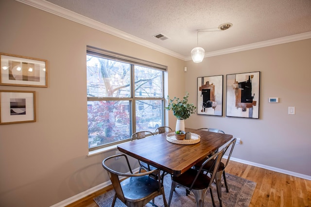 dining room with crown molding, a textured ceiling, and light hardwood / wood-style floors