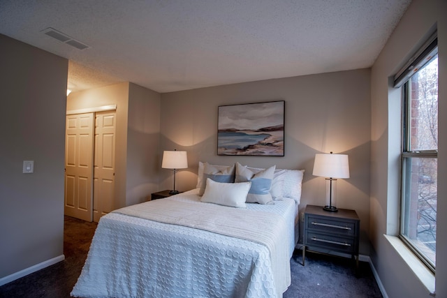 bedroom featuring dark carpet, a closet, and a textured ceiling