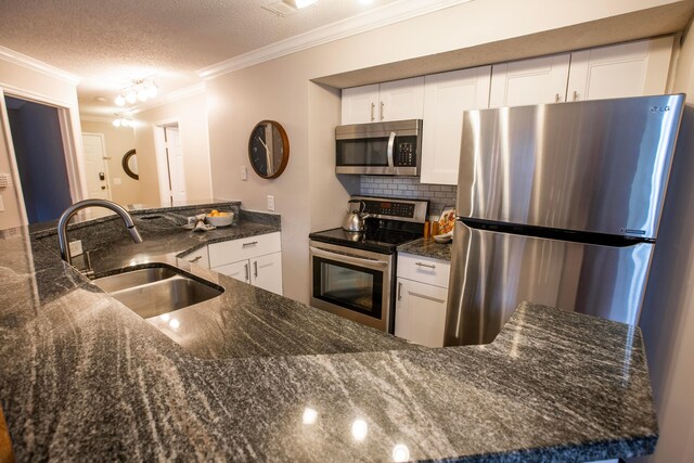 39 Buttles Ave Unit 39, Columbus, OH 43215 - kitchen with stainless steel appliances, ornamental molding, white cabinetry, dark stone countertops, and a textured ceiling