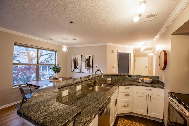 39 Buttles Ave Unit 39, Columbus, OH 43215 - kitchen featuring appliances with stainless steel finishes, crown molding, a textured ceiling, white cabinetry, and pendant lighting