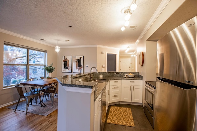 39 Buttles Ave Unit 39, Columbus, OH 43215 - kitchen with appliances with stainless steel finishes, a textured ceiling, white cabinetry, dark stone countertops, and pendant lighting