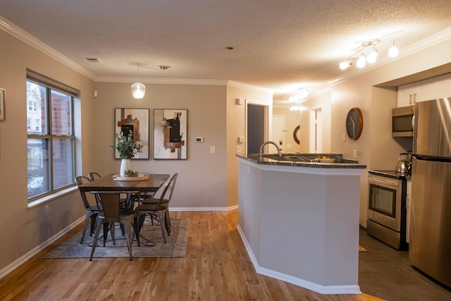 39 Buttles Ave Unit 39, Columbus, OH 43215 - kitchen featuring stainless steel appliances, white cabinets, crown molding, wood finished floors, and a textured ceiling