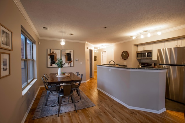 dining area with crown molding, a textured ceiling, and light hardwood / wood-style floors