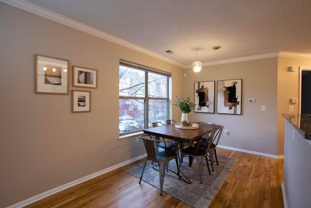 dining space with crown molding, a textured ceiling, and light hardwood / wood-style flooring