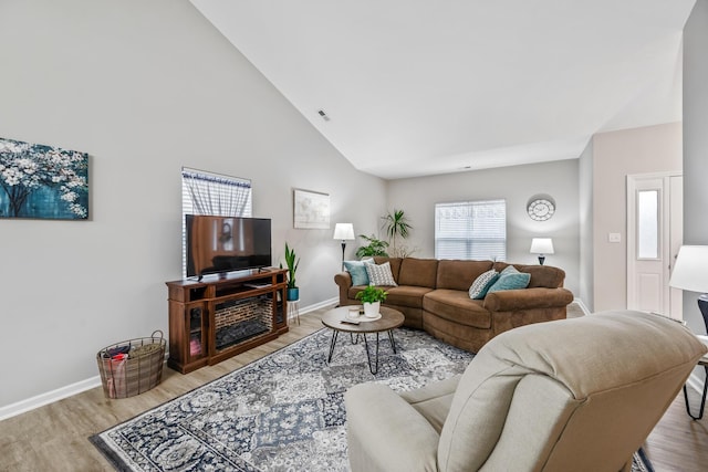 living room featuring high vaulted ceiling and light hardwood / wood-style floors