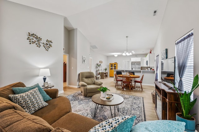 living room featuring light wood-type flooring, an inviting chandelier, and high vaulted ceiling