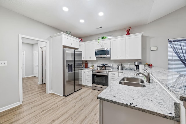 kitchen with white cabinets, light stone countertops, light wood-type flooring, appliances with stainless steel finishes, and kitchen peninsula