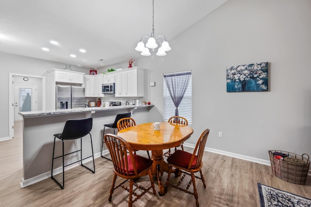 dining area featuring vaulted ceiling, light wood-type flooring, and a chandelier