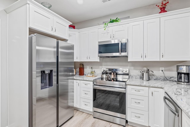 kitchen with light hardwood / wood-style floors, light stone countertops, white cabinetry, and appliances with stainless steel finishes