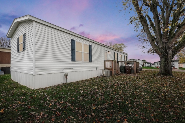 property exterior at dusk featuring a yard and central AC unit