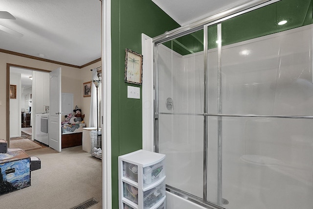 bathroom with washer / dryer, a textured ceiling, a shower with door, and crown molding