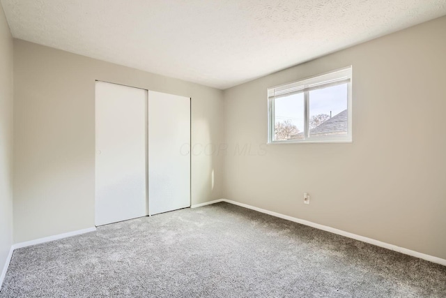 unfurnished bedroom featuring carpet floors, a textured ceiling, and a closet