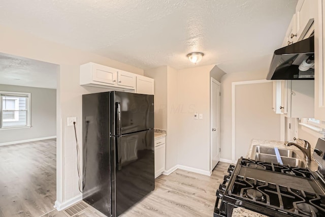 kitchen with black fridge, light hardwood / wood-style flooring, white cabinets, and light stone counters