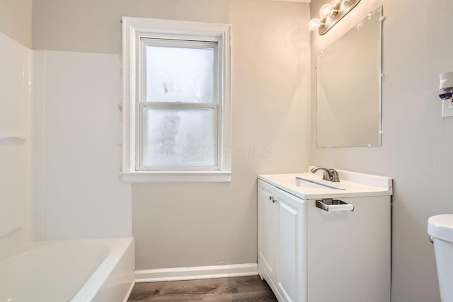 bathroom featuring hardwood / wood-style flooring, a bathtub, vanity, and toilet