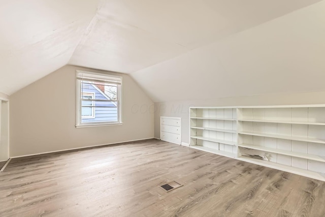 additional living space with wood-type flooring and vaulted ceiling