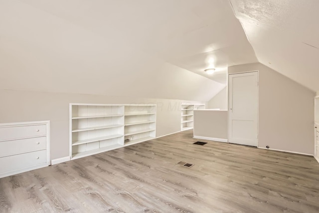 additional living space featuring wood-type flooring and lofted ceiling