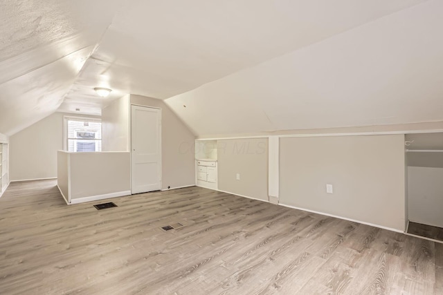 bonus room featuring wood-type flooring and vaulted ceiling